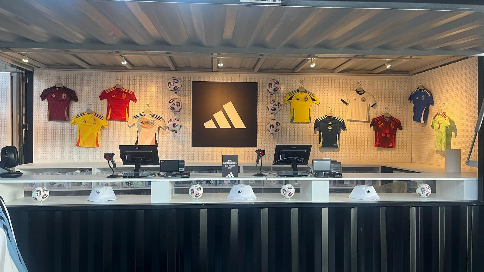 An Adidas store with a number of football shirts lined up against the wall