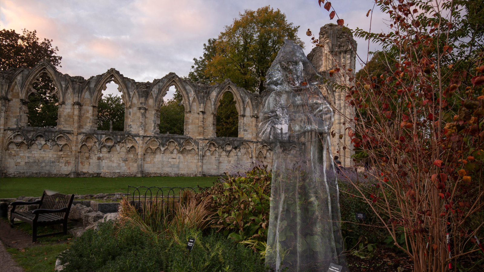 A ghost sculpture of a monk stands by the ruined stone abbey in the Museum Gardens in York.