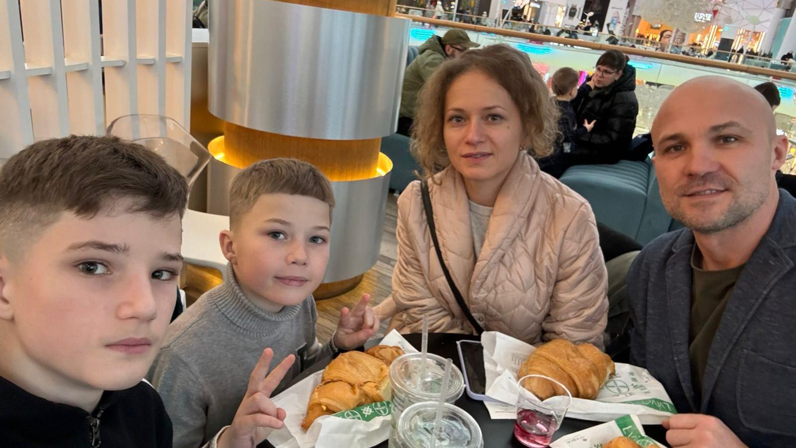 Mum and dad sat with their two boys at a restaurant with croissants.