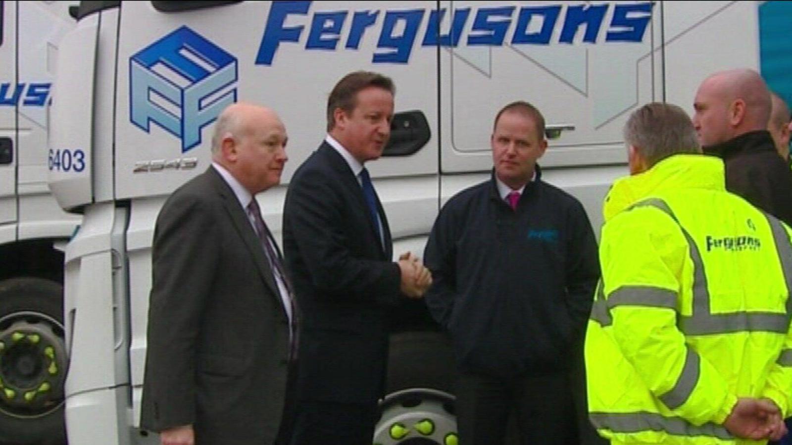 An archive picture showing former Prime Minister David Cameron, who is wearing a blue tie and a suit, shaking hands with a team of several workers from Fergusons Transport.