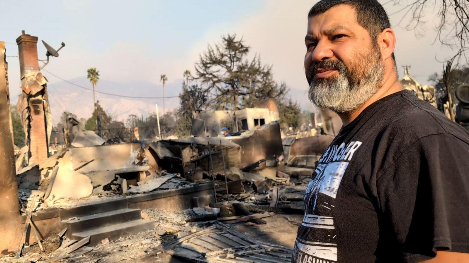 Hipolito Cisneros stands in front of the ashes of his home in Altadena, California