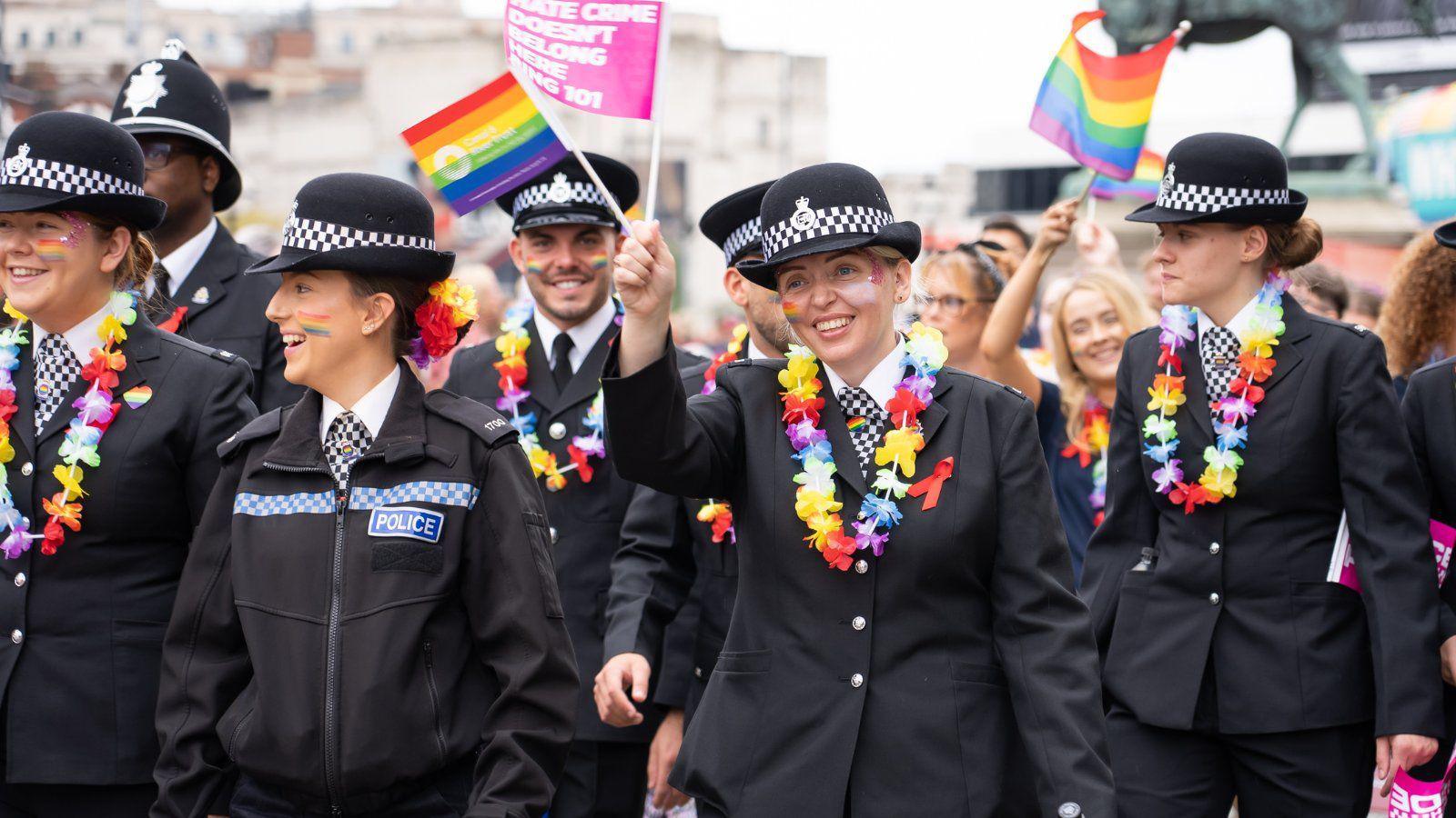 Merseyside Police officers waving pride flags for Liverpool's Pride march in 2022