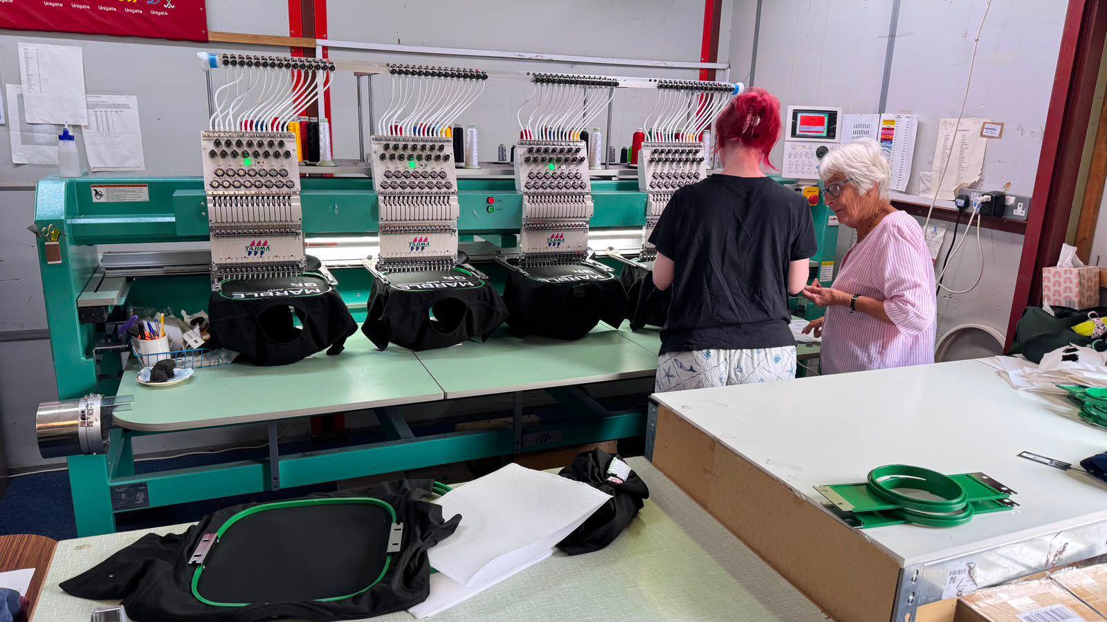 Two women are chatting next to some branding machinery