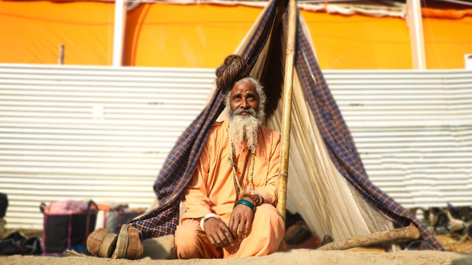 Baba Amarnathji, a 60-year-old saffron-robed monk, sits outside a little tent he's set up for himself with cloth and plastic sheets over three bamboo poles