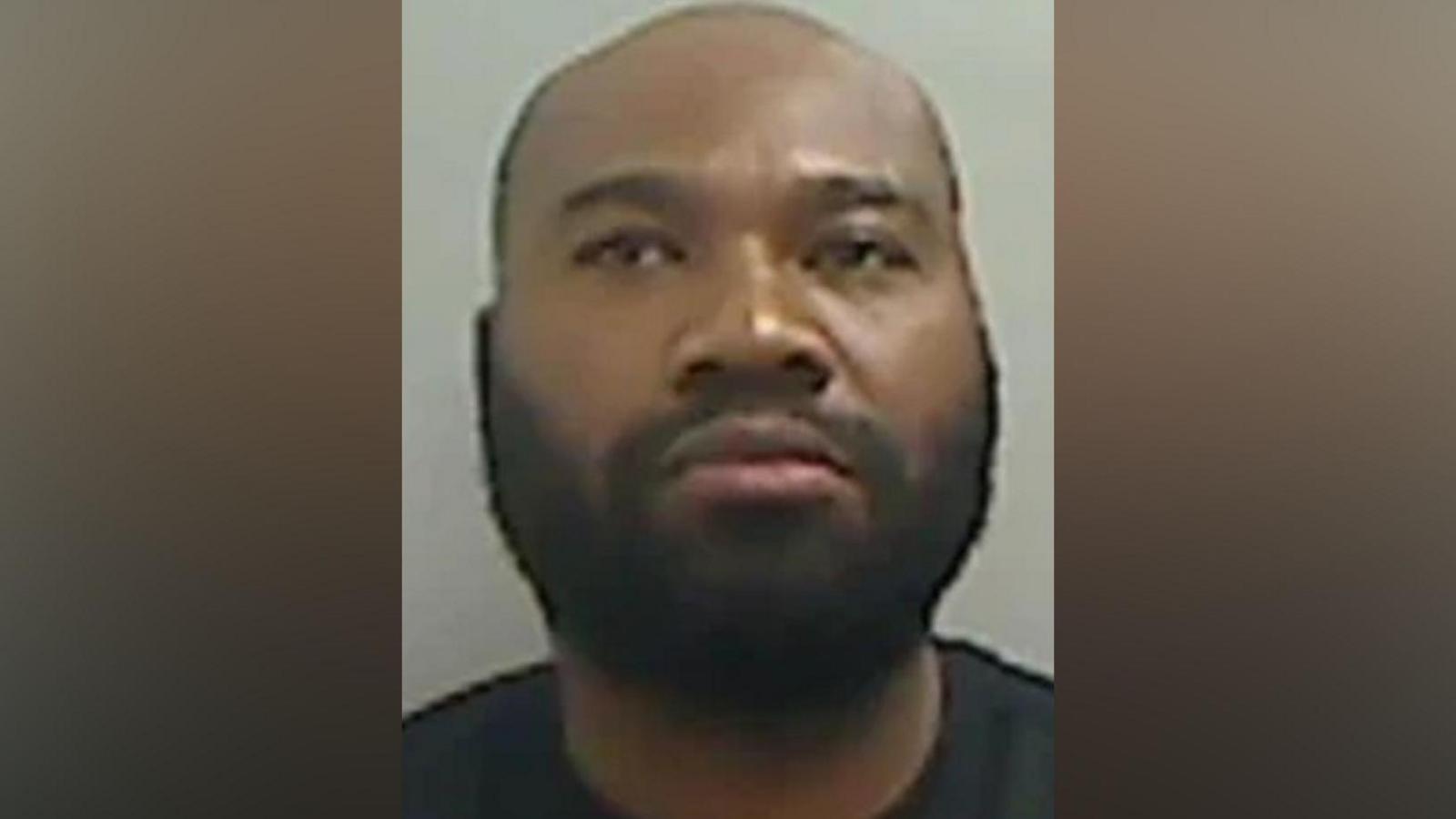 Mugshot of Hammond. He has a thick black beard and a bald head and is unsmiling. 
