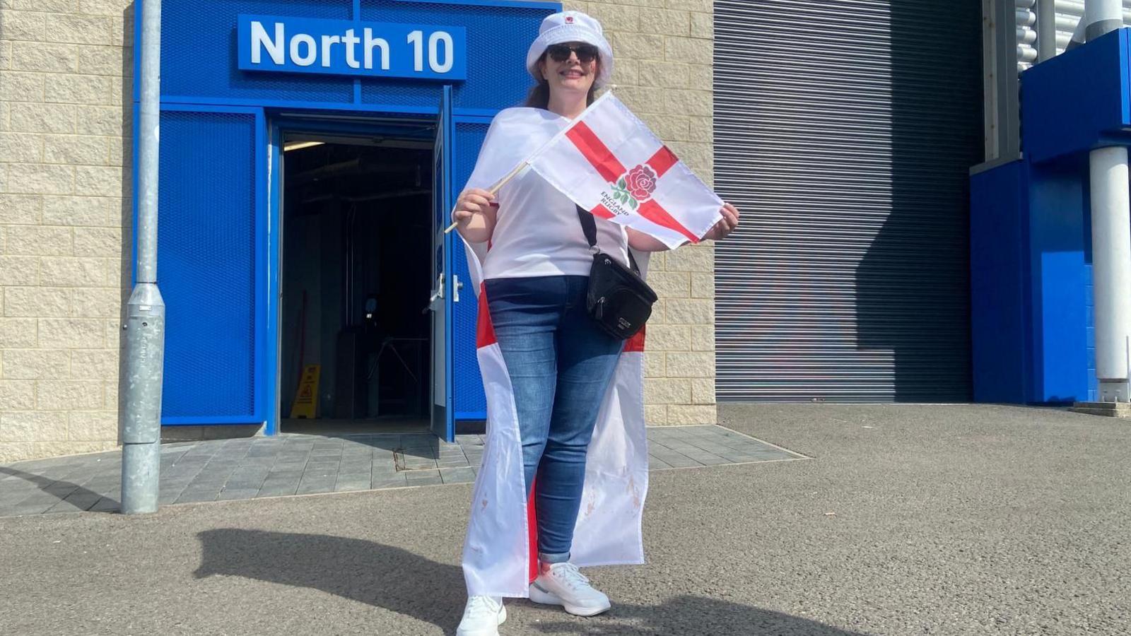 A woman holding a St George's flag with another over her shoulders.