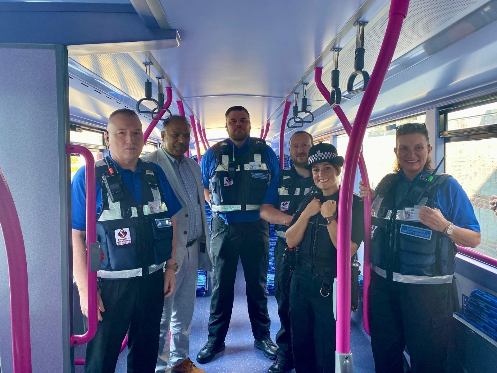 A photo of four transport officers, deputy council leader Amjid Wazir and Chief Inspector Laura Davies from Staffordshire Police standing inside a bus with pink and blue interiors