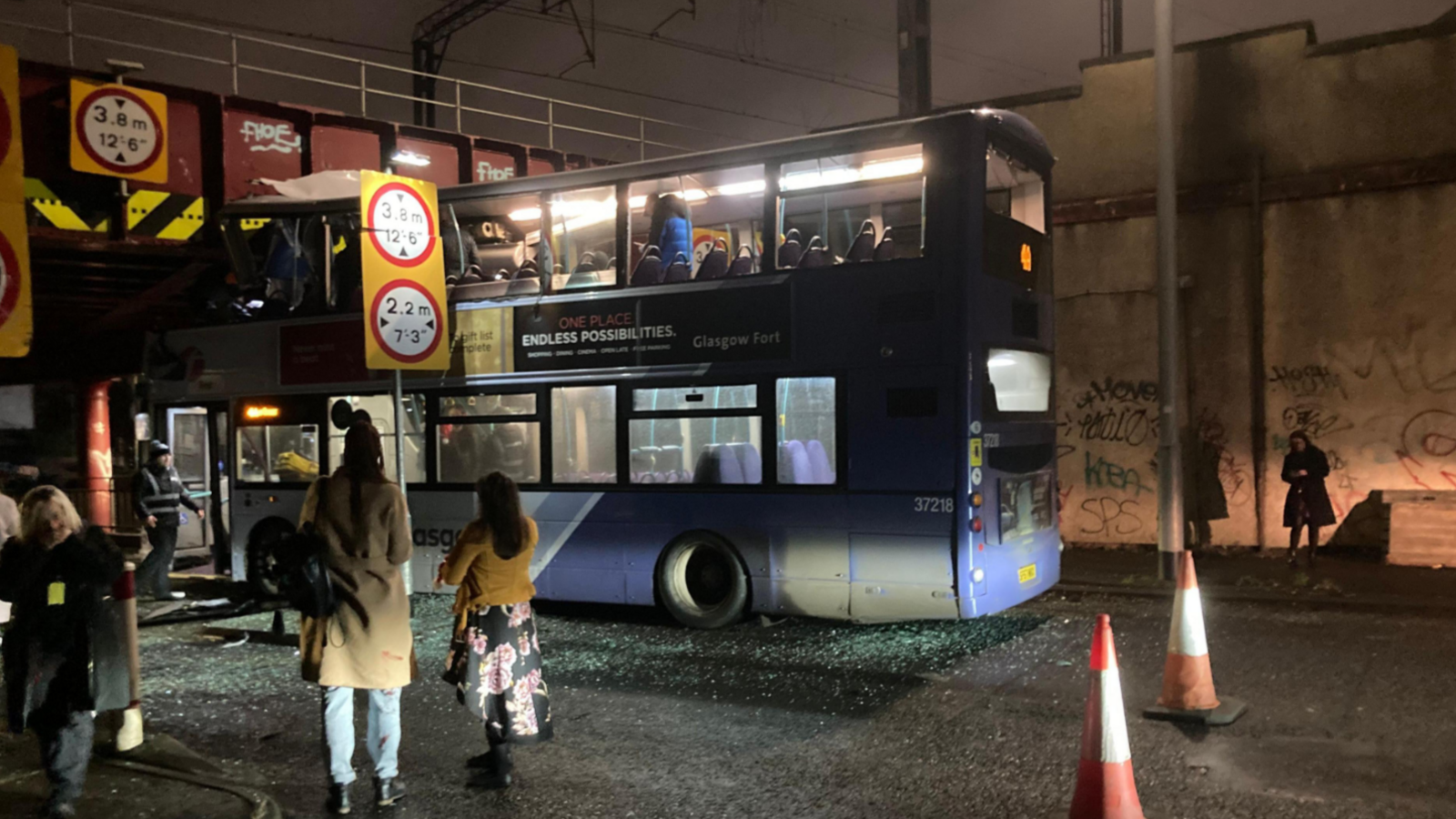 A First Bus wedged under the railway bridge at Cook Street/Commerce Street in Glasgow city centre. There are some people on board while others look on from the pavement