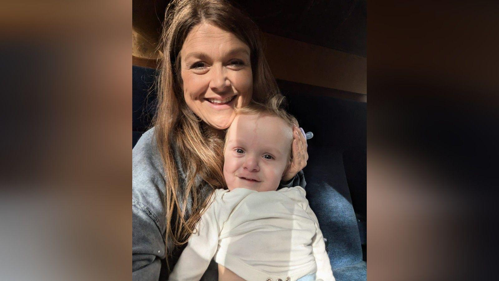Harvie Strange holding Rafferty. They are both smiling for the camera.