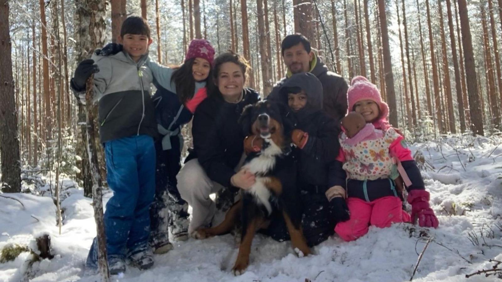 A recent photo of Sarah Recinos Ralda in a snowy forest with her husband, her four young children and their pet dog Mali