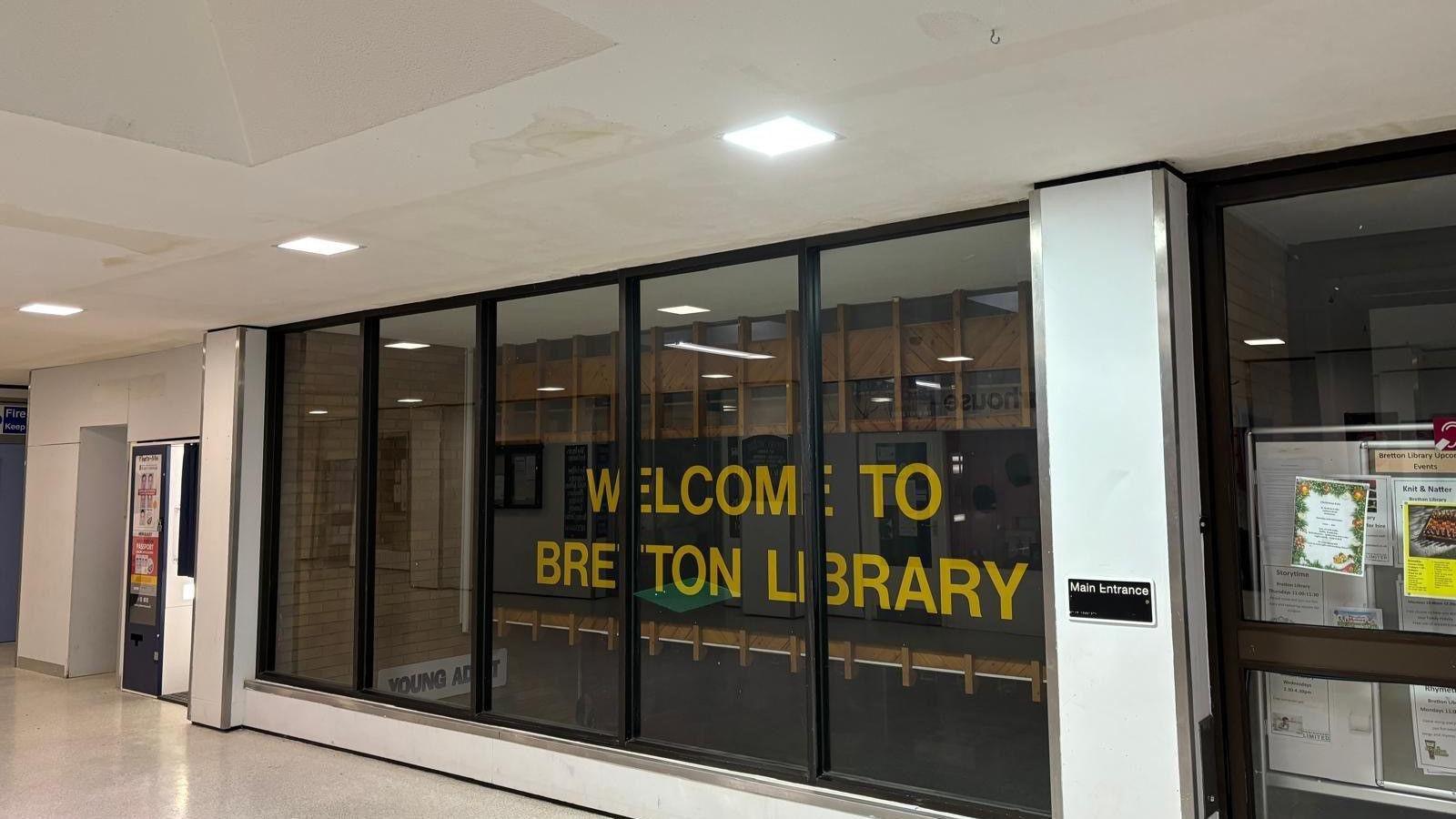 Exterior of Bretton Library - glass window with a yellow "Bretton Library" sign 