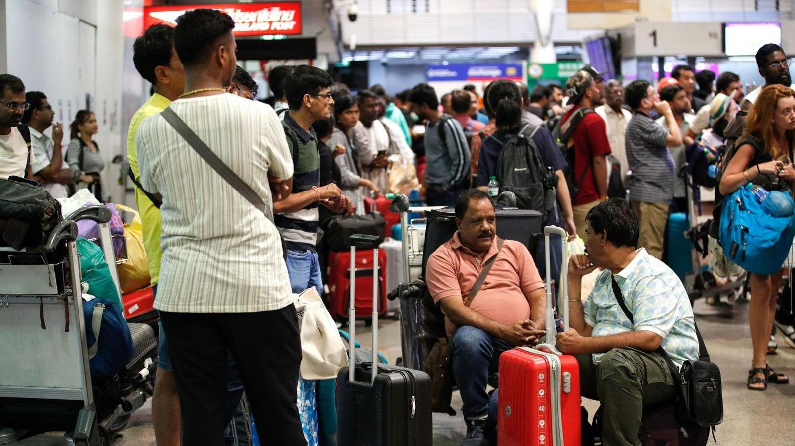 Passengers wait to check in at Don Mueang International Airport in Bangkok, Thailand during the global IT outage