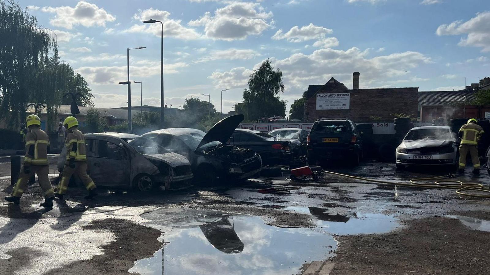 Two fire officers walking away from burnt out cars in a parking yard