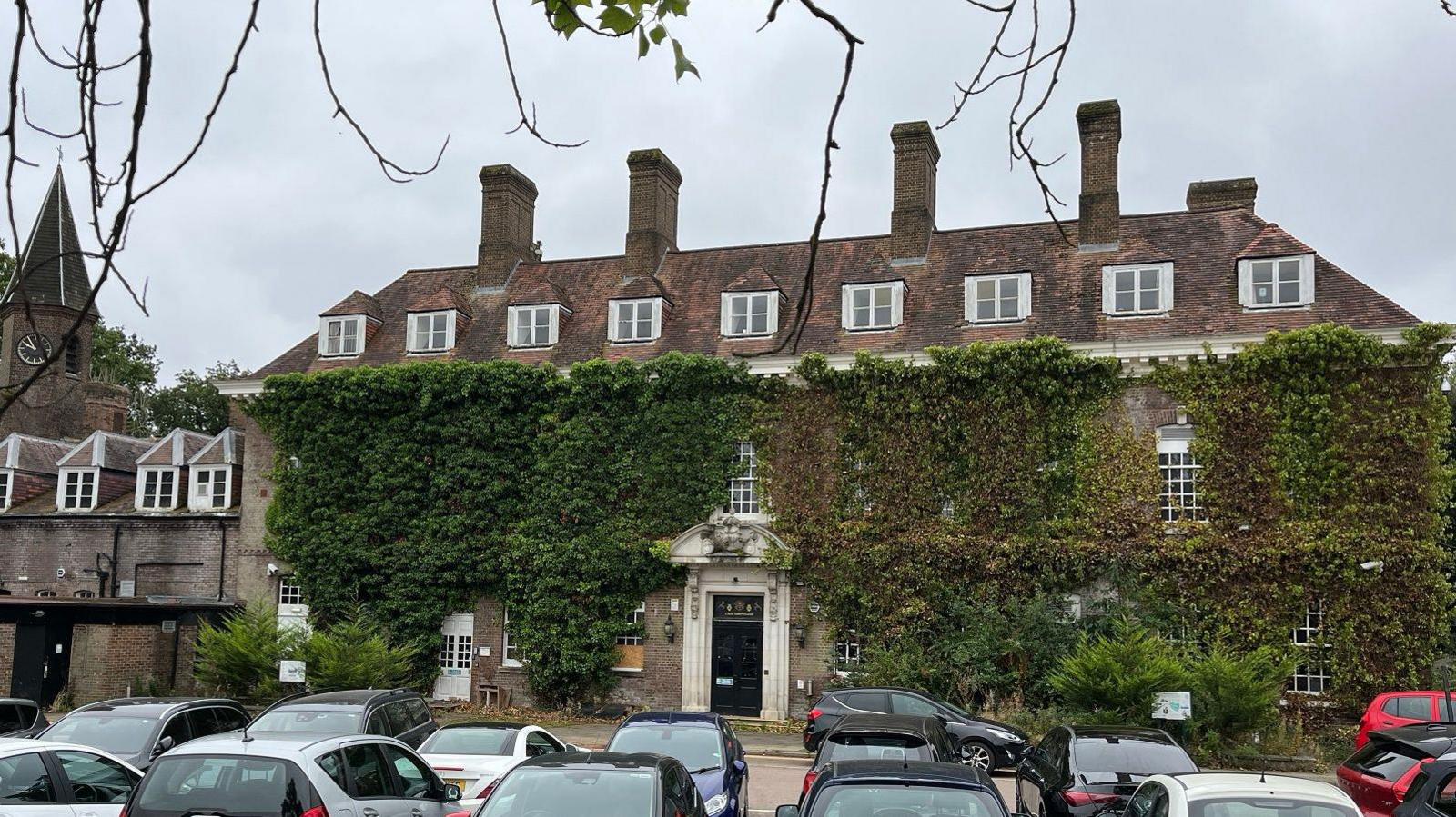 A large manor house covered in ivy with many rooftop windows