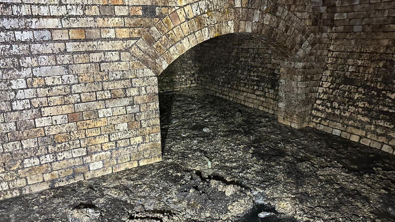 A brick built historic sewer with and arched chamber full of large amounts of fat and grease that has built up. 
