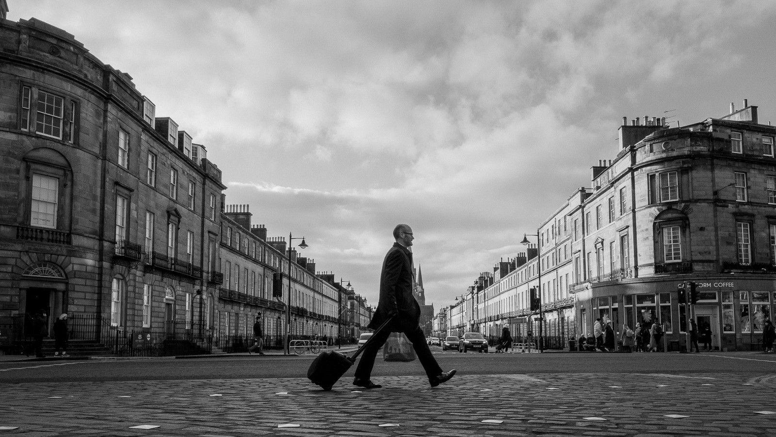 A man walks across a cobbled street