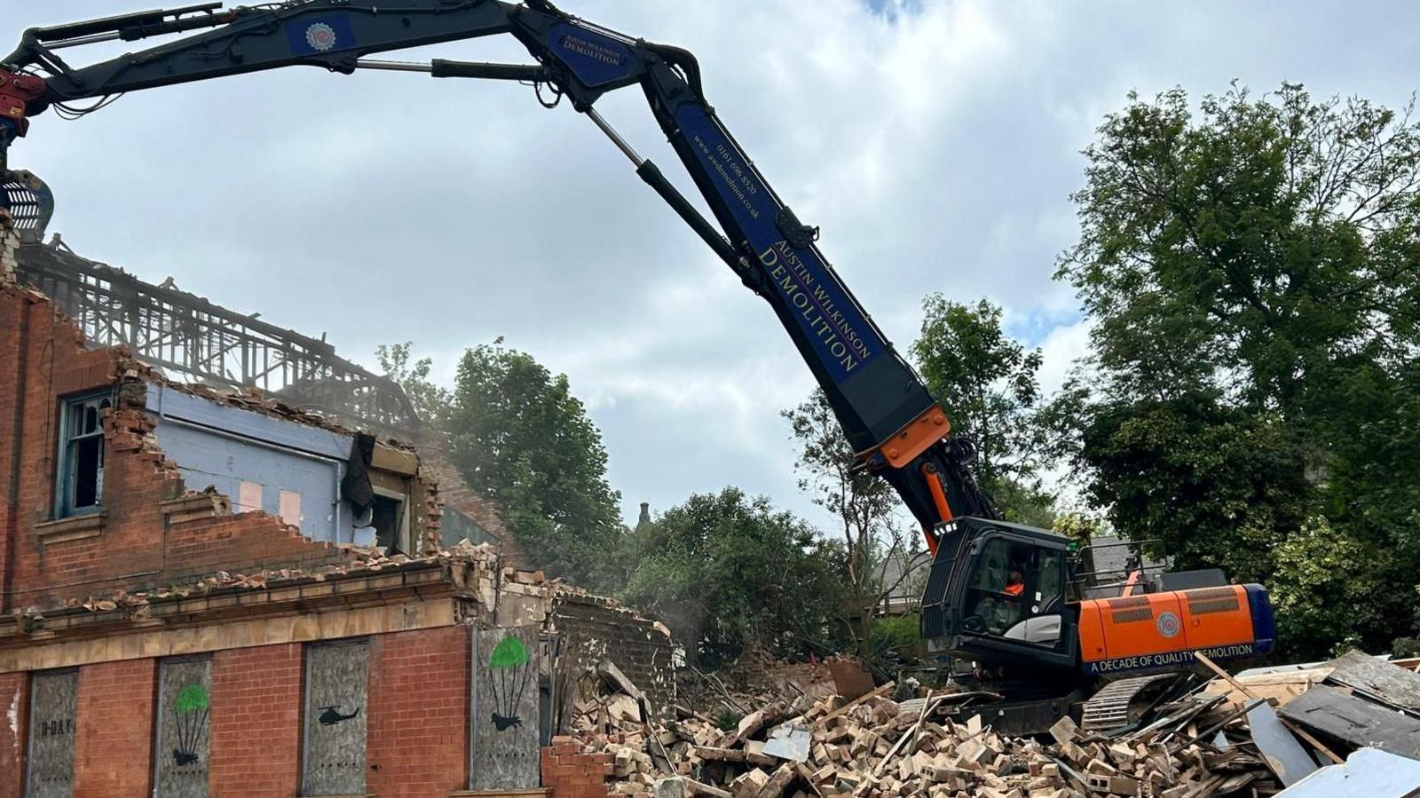 Demolition at the site with a machine pulling down walls