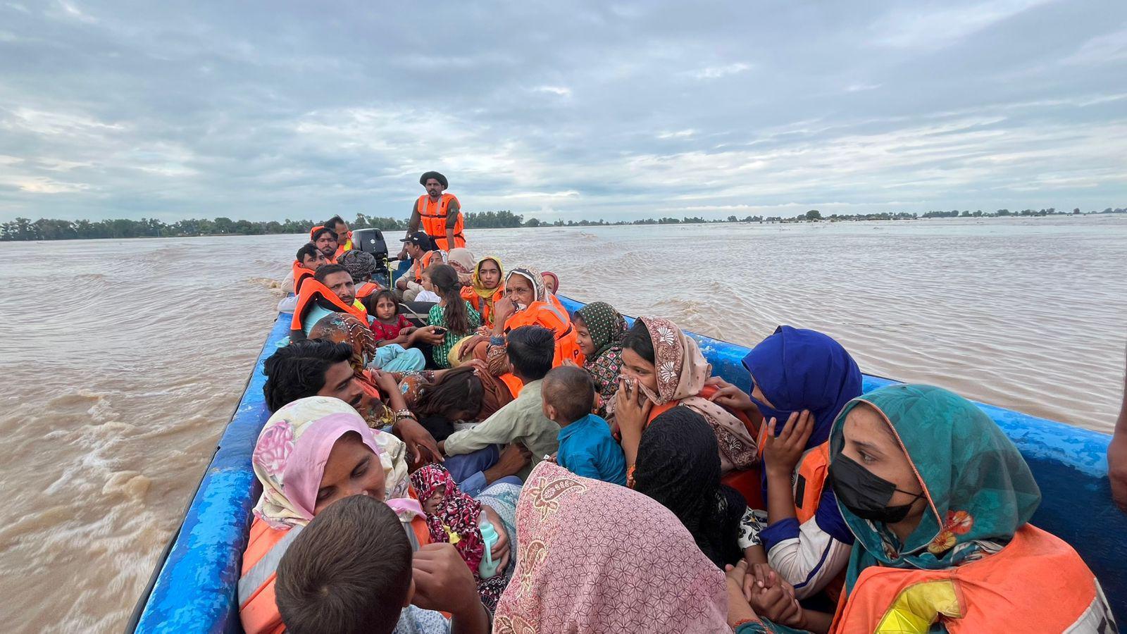A full small boat full of evacuees sails into a river