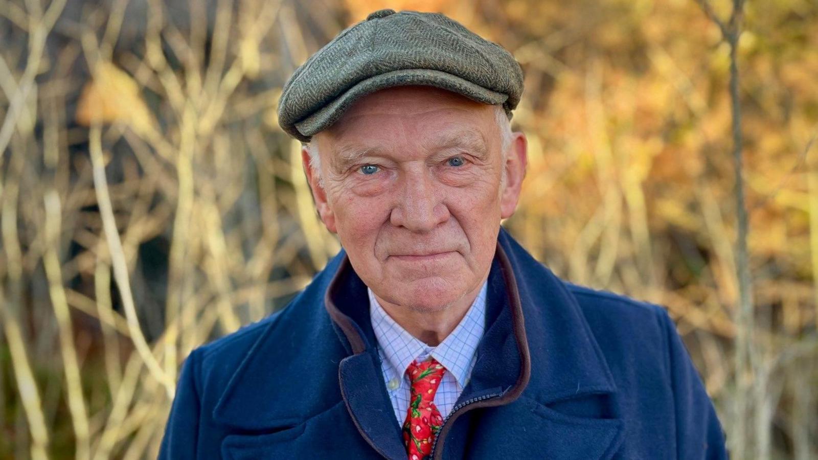 Tom Wood wearing a green cap, blue jacket and red tie