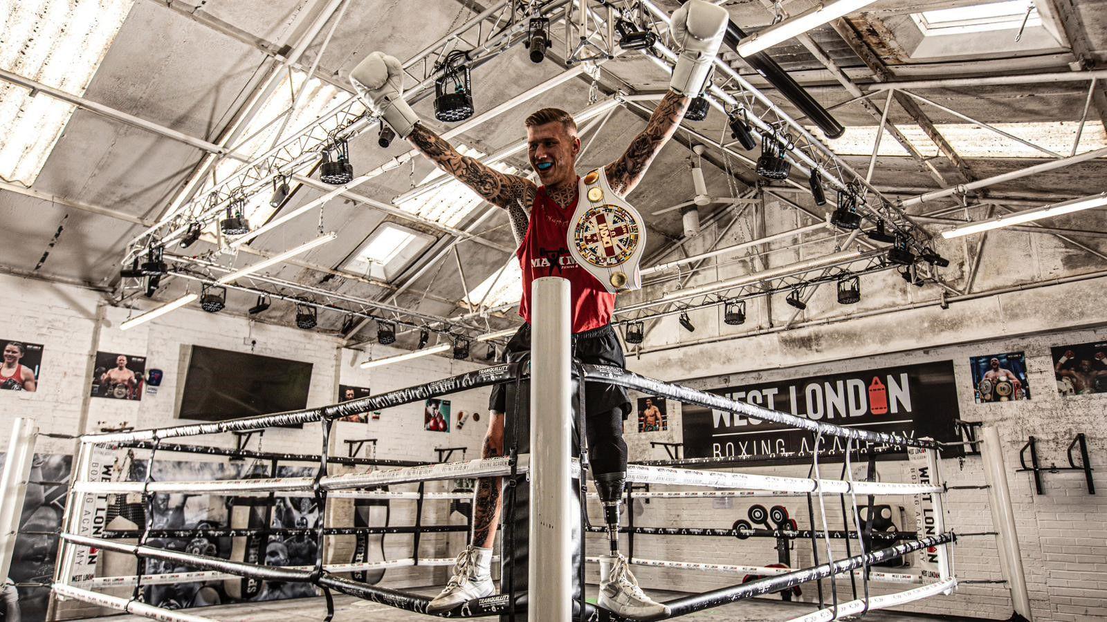 Matt Edwards stood on the ropes in the corner of the ring wearing a belt on his shoulder and holding his hands in the air