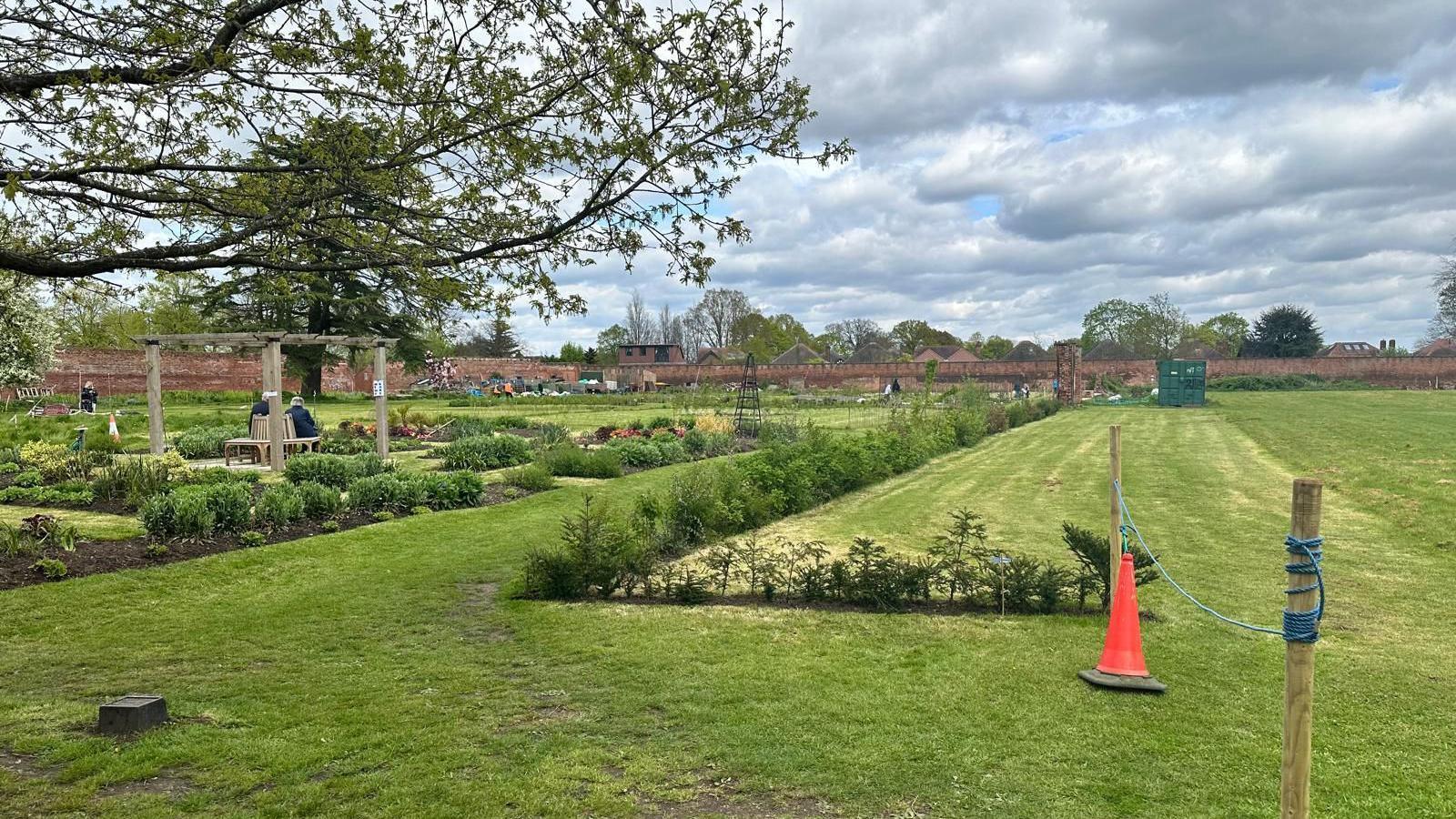 View across the gardens, showing newly-planted beds and hedges, with the wall in the middle distance