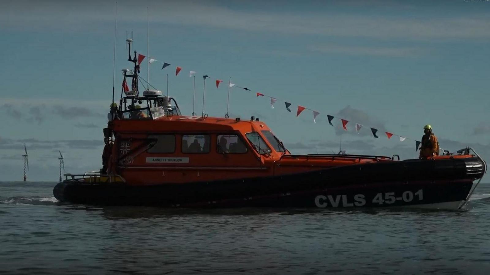 A sideways view of the orange and navy lifeboat with bunting going from the top to the front. The name Annette Thurlow can be seen on the nameplate.