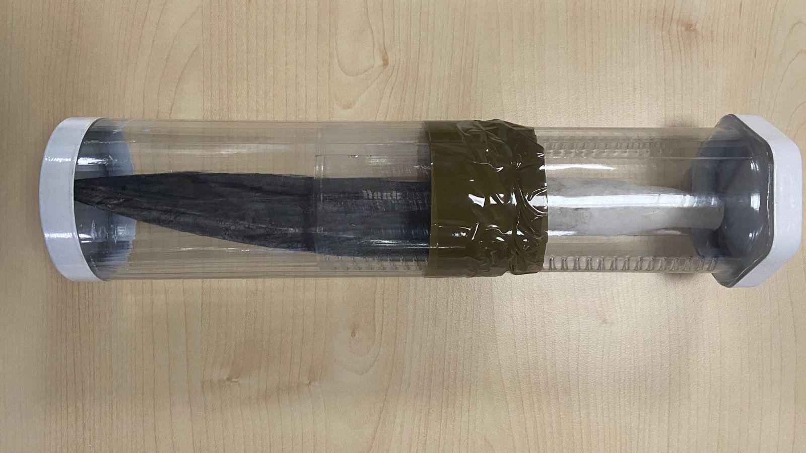 A black knife with a white handle in clear plastic box