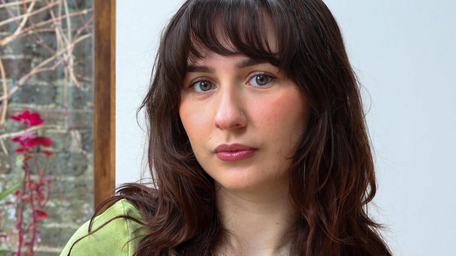 Portrait photo of Adele Walton who has long wavy dark brown hair looking to camera.