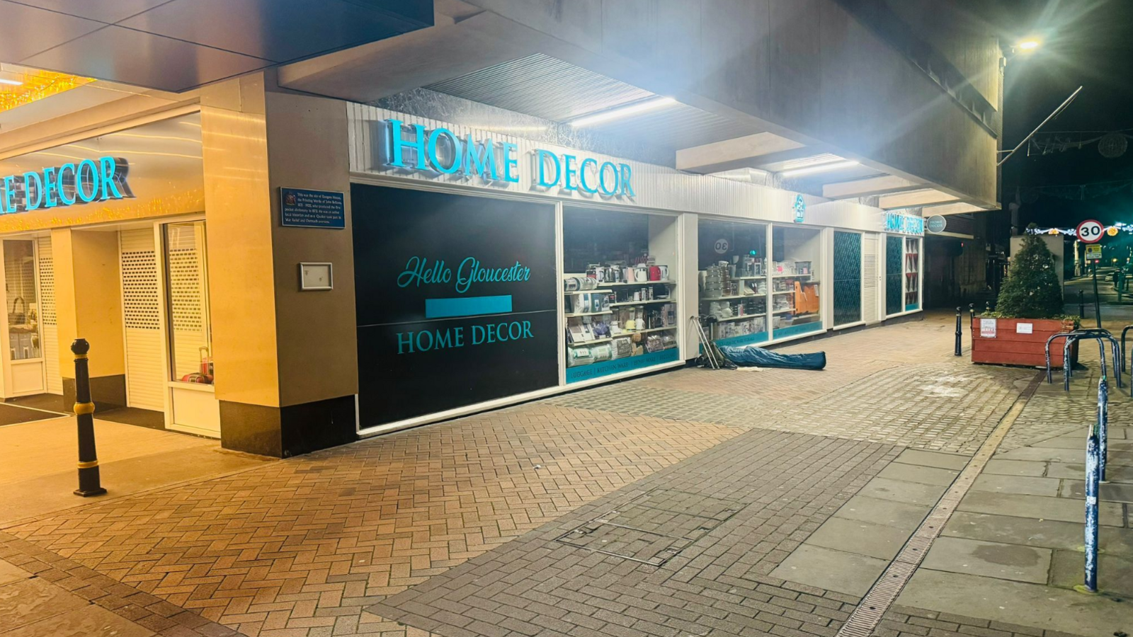 A person sleeps rough outside a home decor shop in a blue sleeping bag