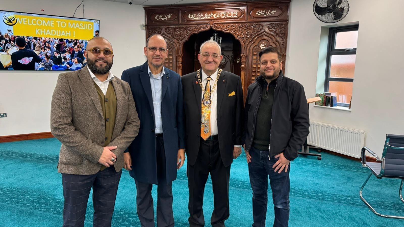 Marco Cereste, wearing his chain of office, standing alongside other people at the mosque.