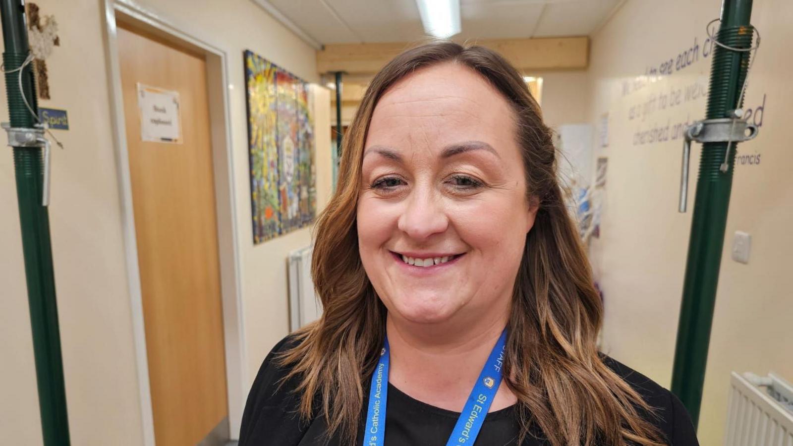 Headteacher Kay Methven stands in hallway in front of props holding up ceiling 