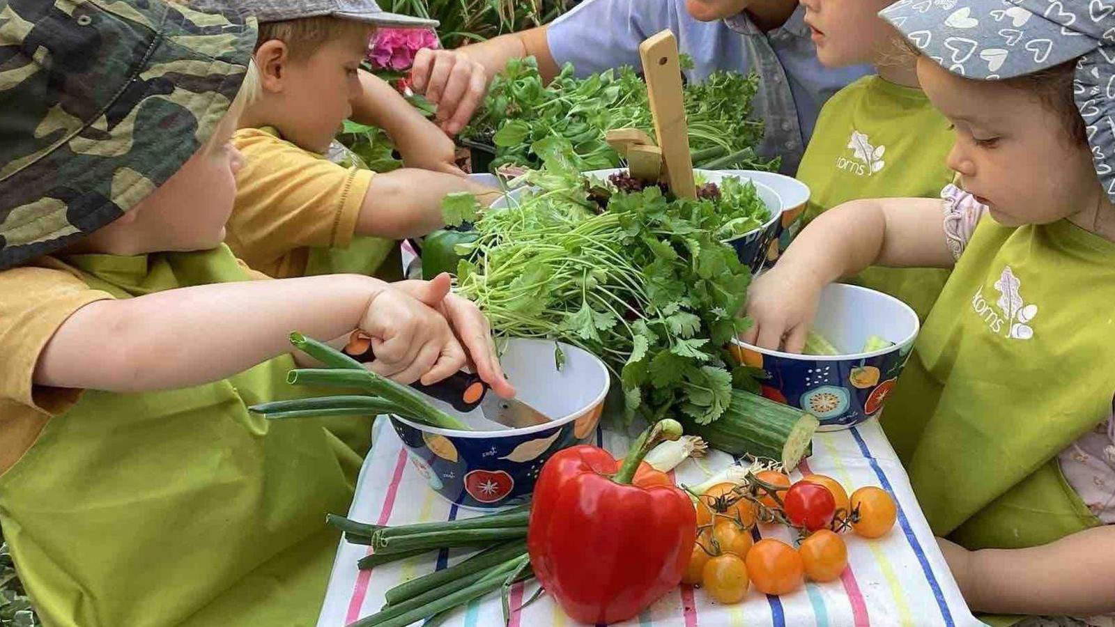 Kids chop vegetables at a table in a nursery