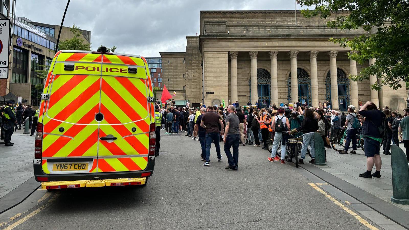 A police van in front of people