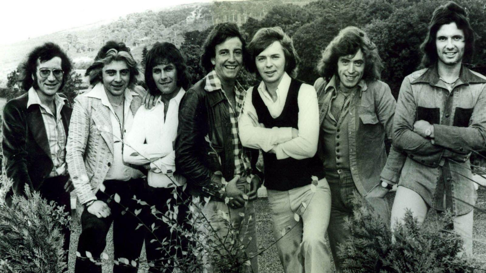 A black and white photo of members of the Miami Showband. There are seven men in total, all dressed in the fashions of the time.