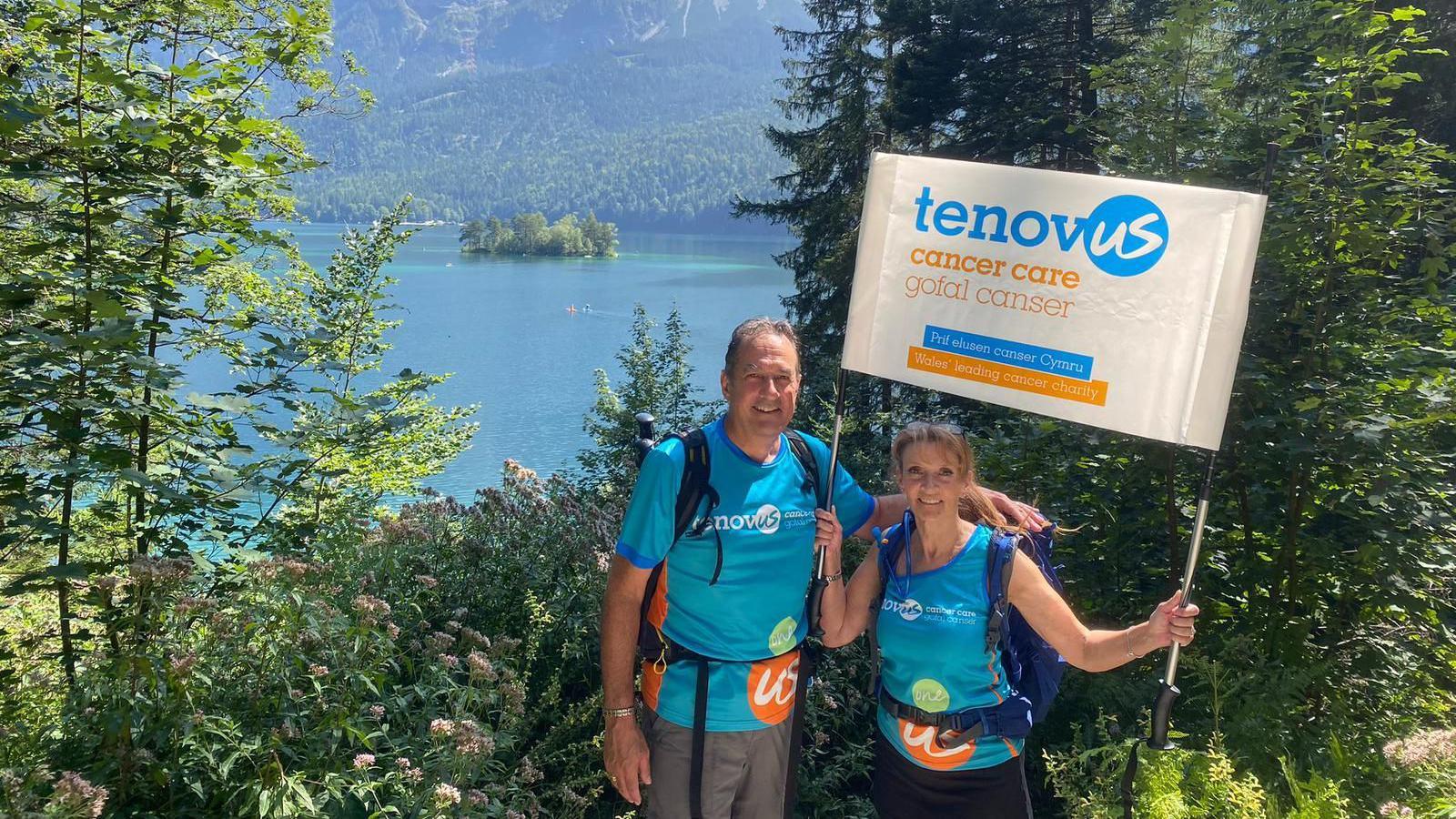 Dawn and her husband Paul standing in front of the river holding up a Tenovus Cancer Care banner. The both wear blue tops to represent the charity.