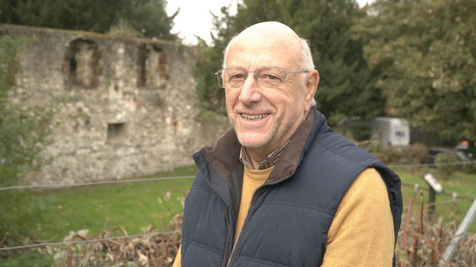 Philip Badman, secretary of Hallling Historical Society in front of last remaining wall of 12th Century Bishop's Palace in Halling