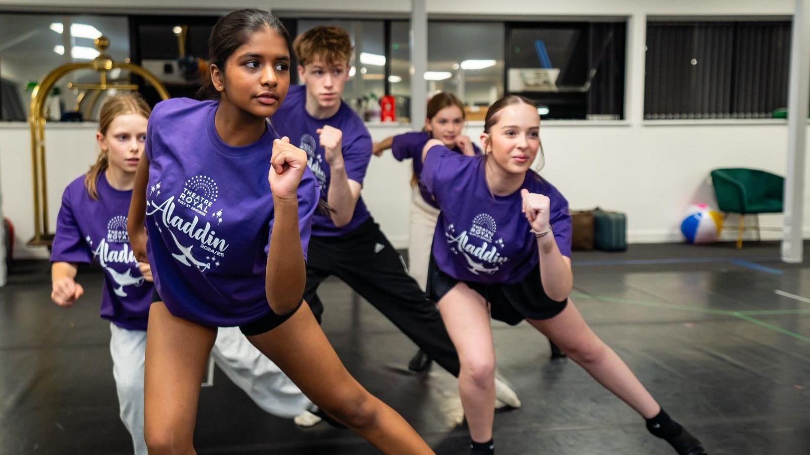 A group of young performers go through their dance routine ahead of appearing in Aladdin at the Theatre Royal in Bury St Edmunds. They are all wearing purple T-shirts with the pantomime's logo on them