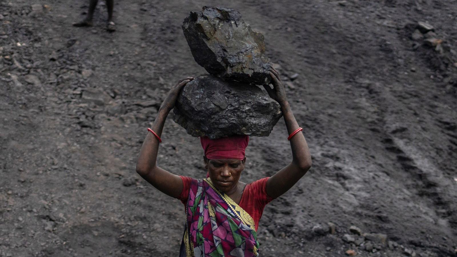 A worker wearing a colourful saree carries coal on her head at a mine in the outskirts of Dhanbad, Jharkhand, India, on Friday, Aug. 30, 2024. The Indian state of Jharkhand has passed a bill imposing mining taxes, according to people familiar with the matter, a move that's set to inflate the prices of minerals - from coal to bauxite.