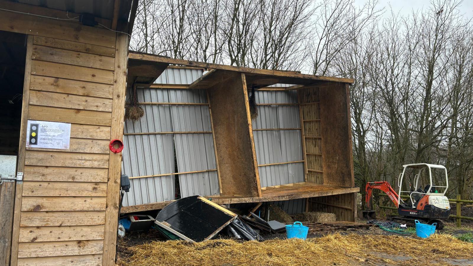 Wooden horse stables lopsided with damage to the corrugated metal and roof