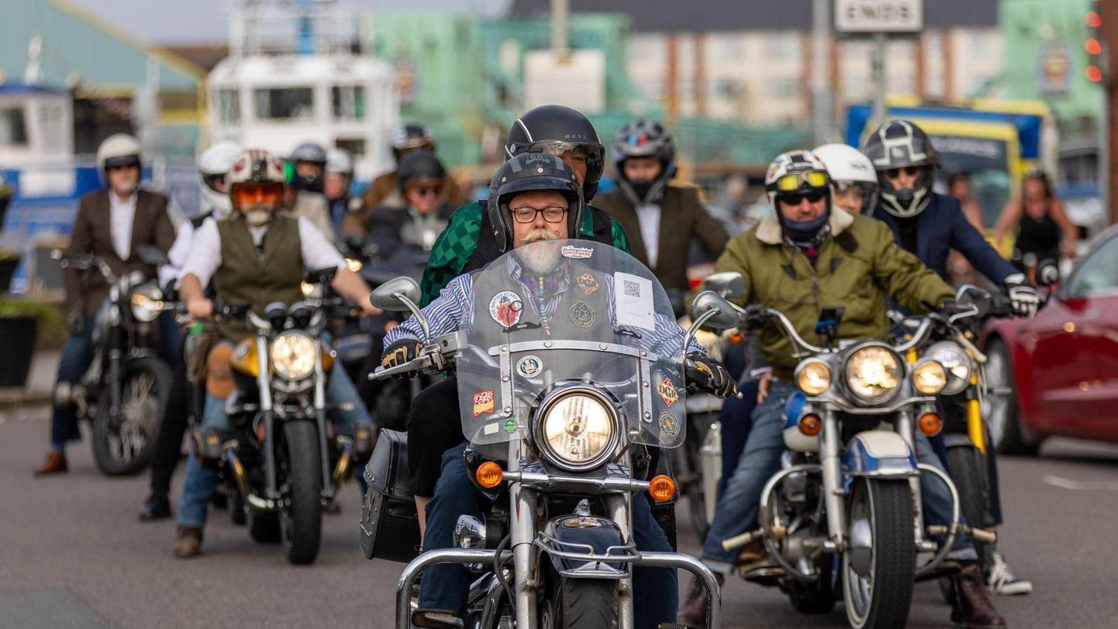 A large group of men in suits riding motorcycles.