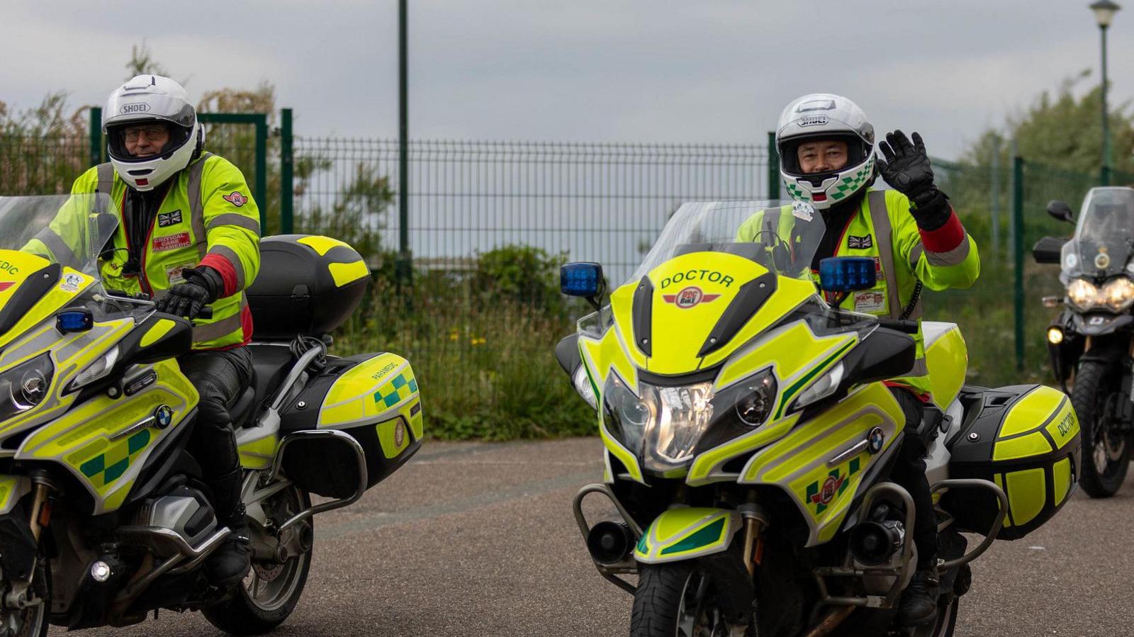 Two doctors on hi-vis bikes and in uniform. Their bikes say "doctor" on the front.