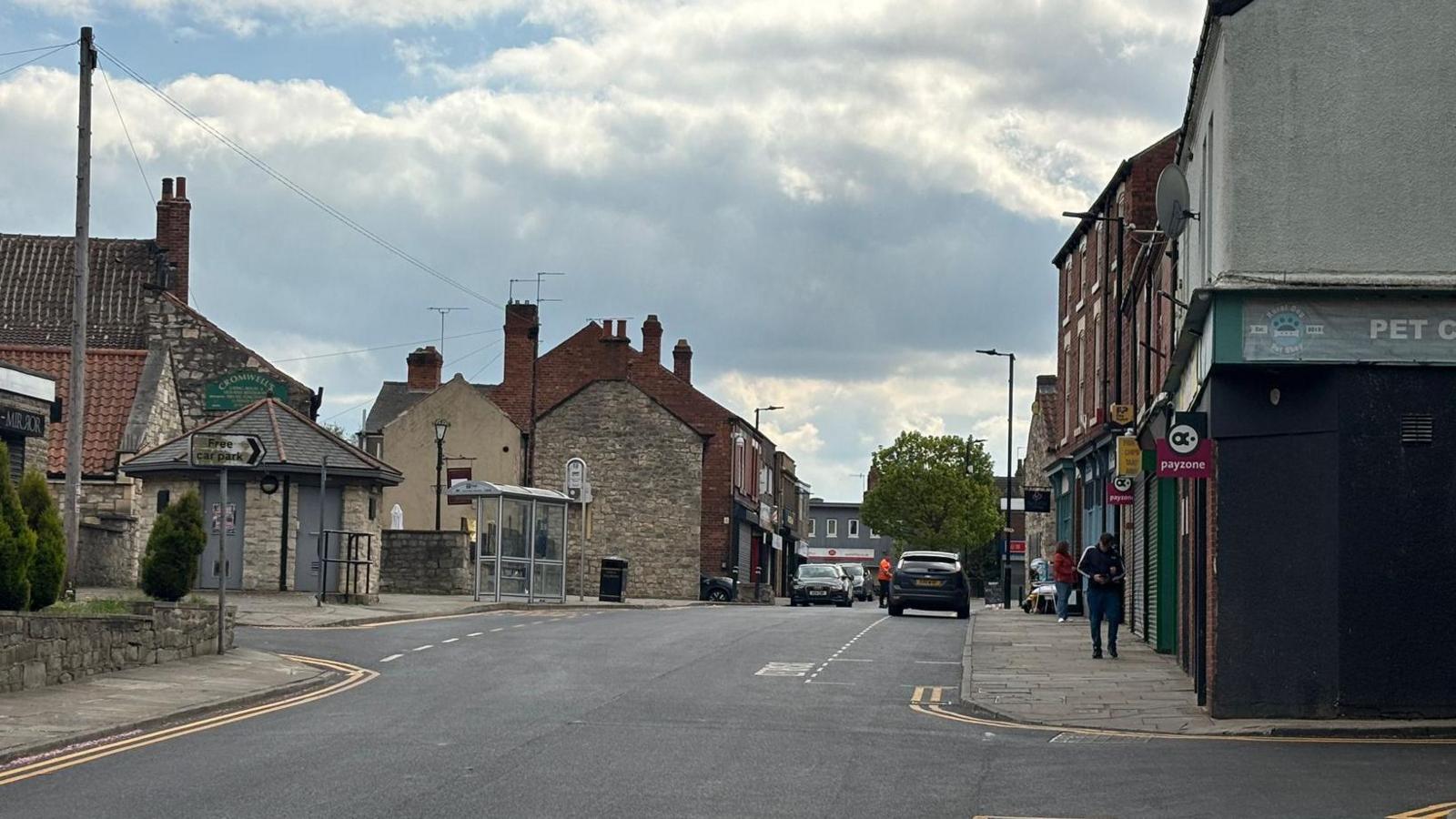 A high street in a town, which is made up of shops and housing.
