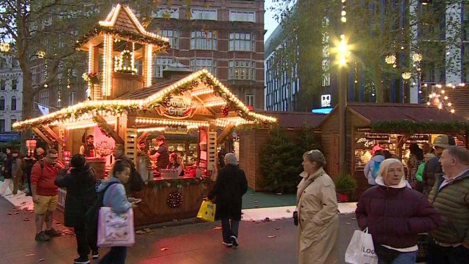 Leicester Square's winter market with wooden chalets and people walking by