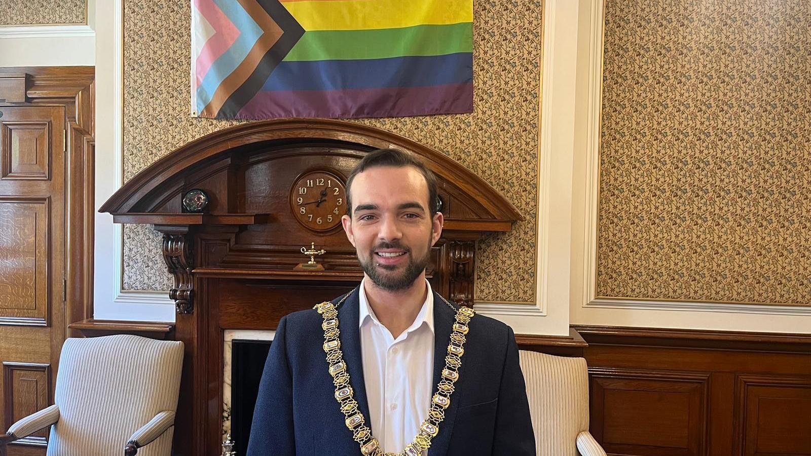 Lord mayor of Belfast in front of a pride flag