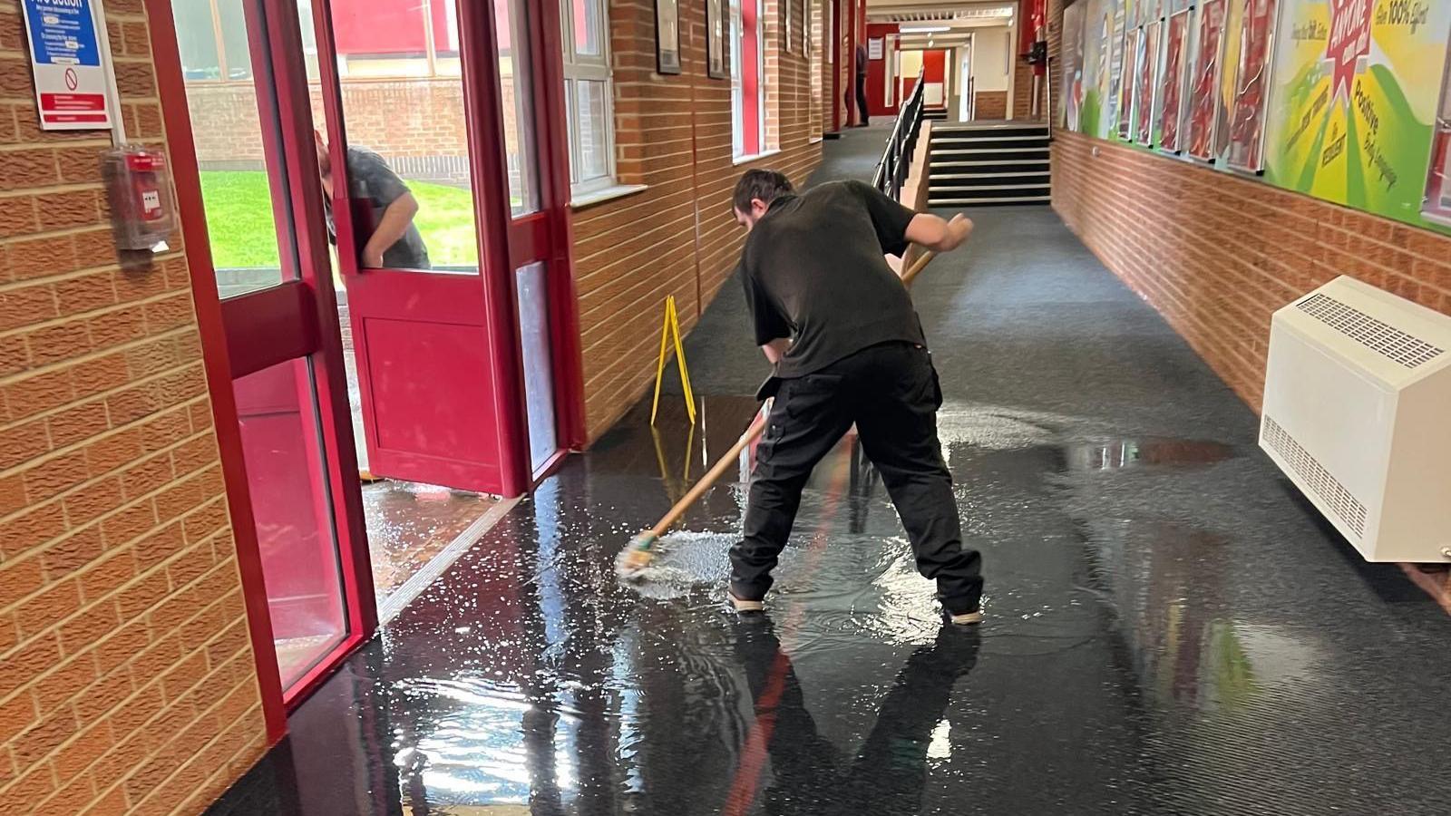 A man cleaning up water from the corridors of the school