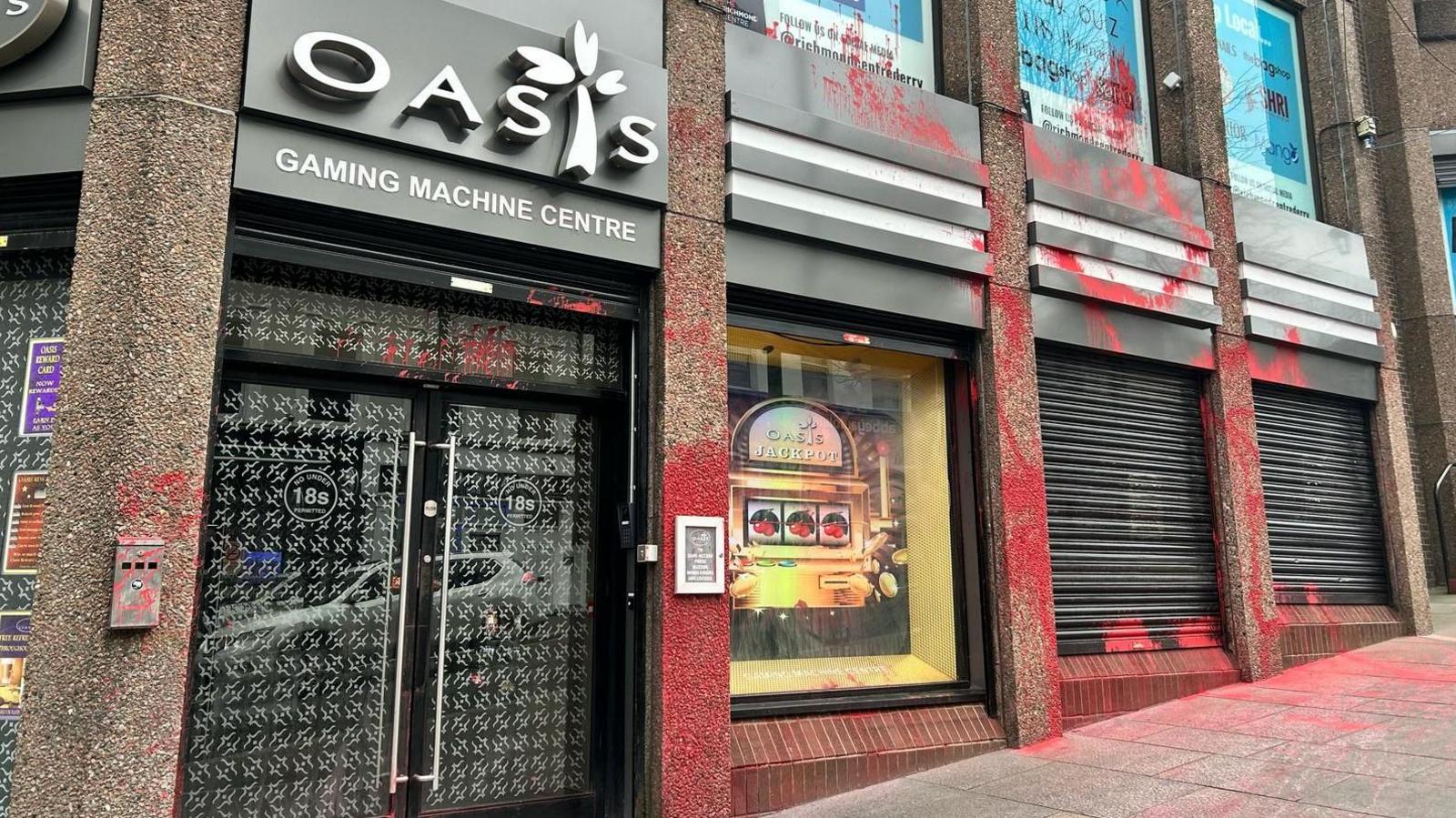 Red paint seen splatted over the exterior of Oasis Gaming Machine Centre in Shipquay Street in Londonderry. Two shutters are down.