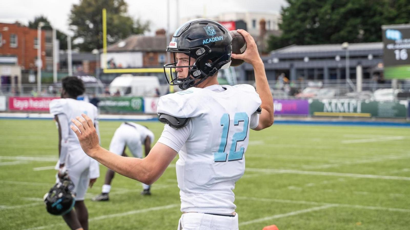 Sam Fenton shapes to throw the football, with team-mates in the background