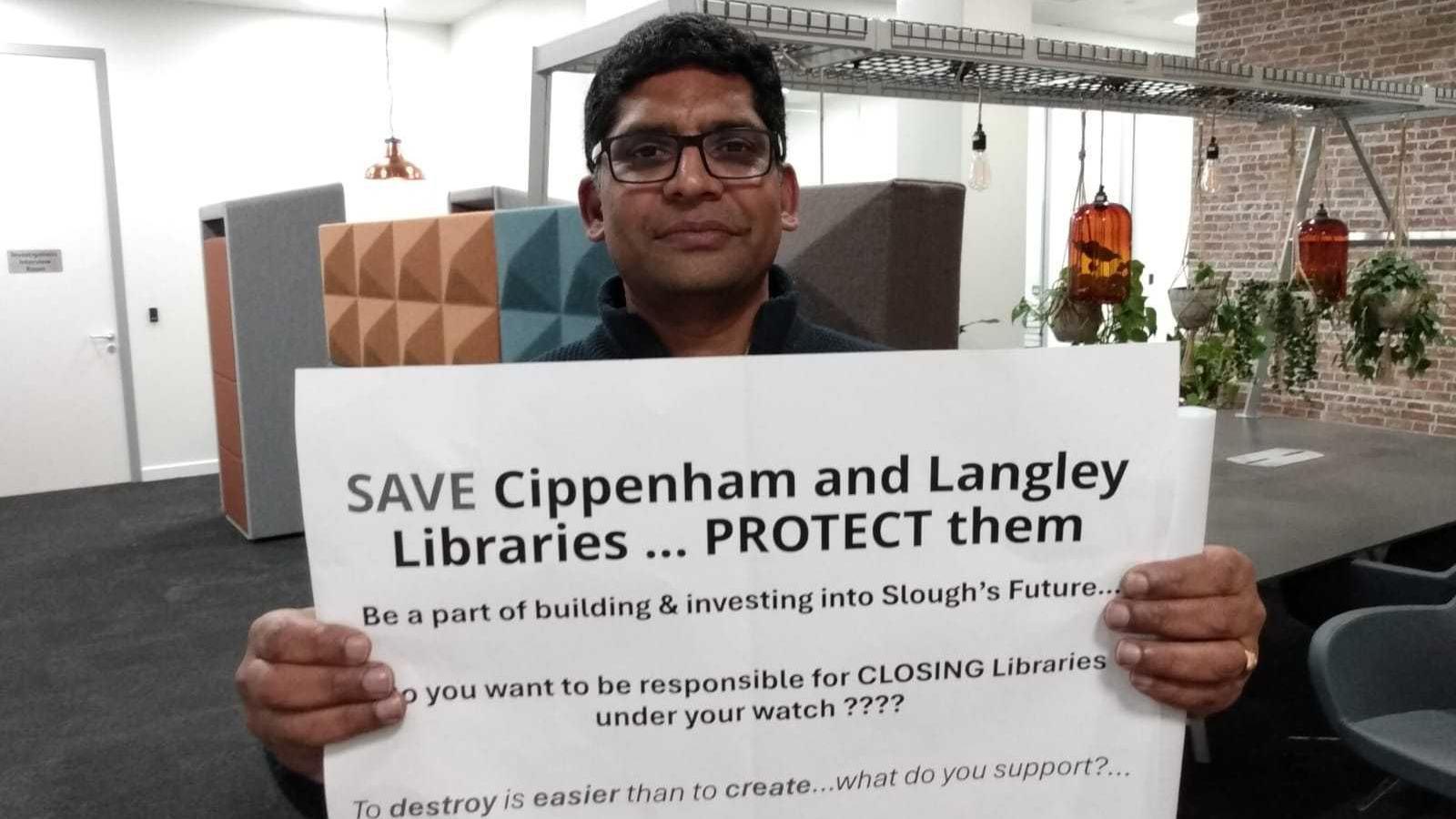 A man with dark hair and glasses holding up a sign saying "Save Cippenham and Langley libraries".