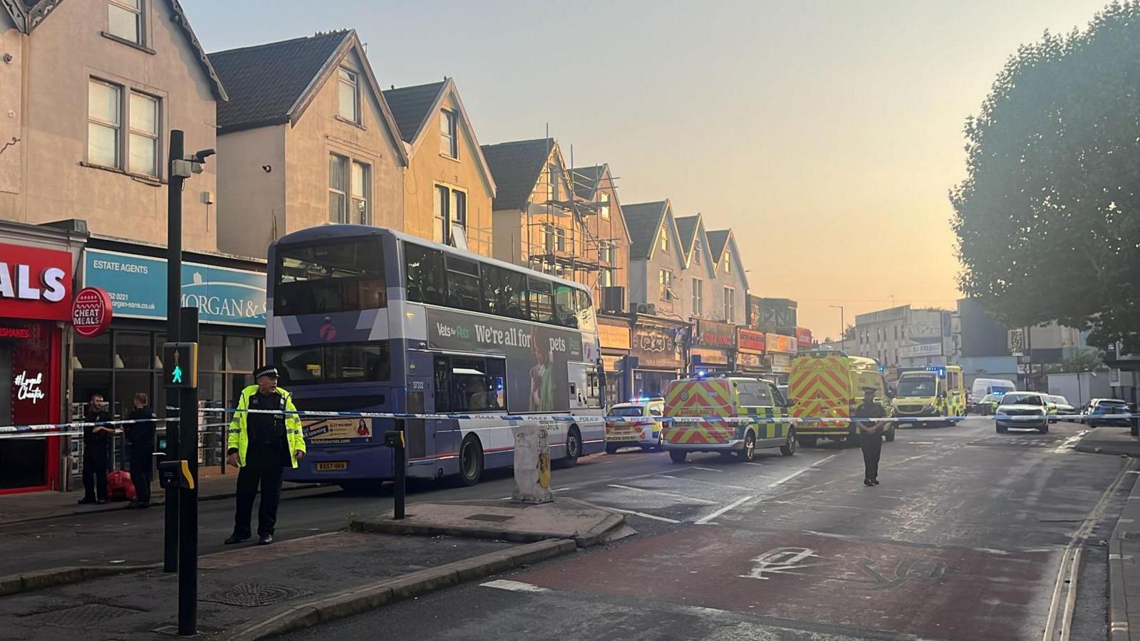 A road closure on Stapleton Road in Bristol with police tape, police officers and an ambulance.