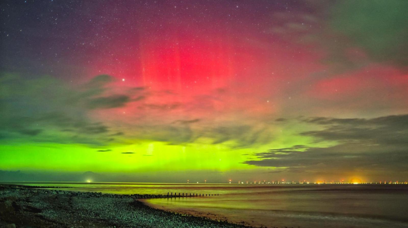 A mix of green and pink colours can be seen over the ocean.